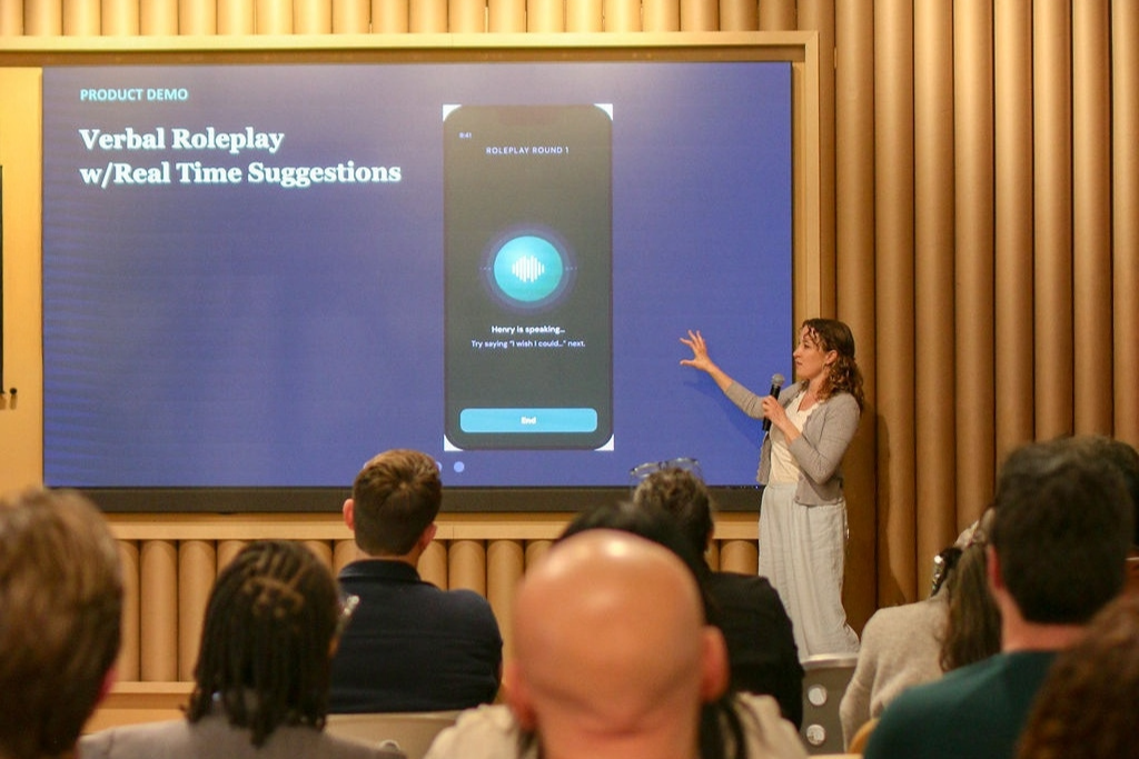 A speaker presenting a prototype on stage to attendees during Startup Weekend San Diego.